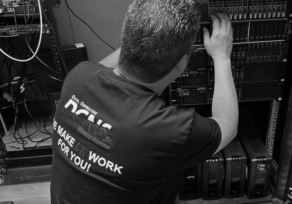 DCNS employee on the scene of an IT job fixing server while wearing DCNS t-shirt